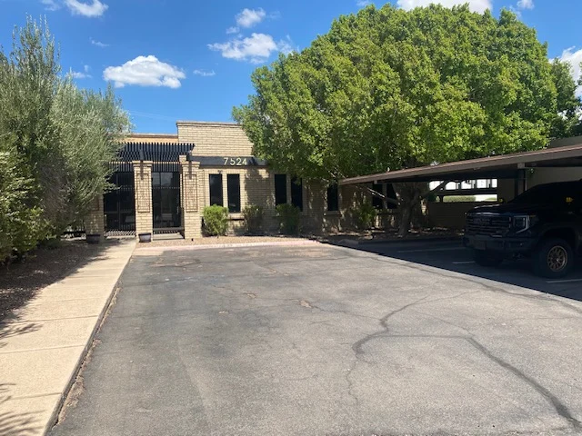 Masonry exterior with 7524 visible above the entrance and covered parking alongside the drive.